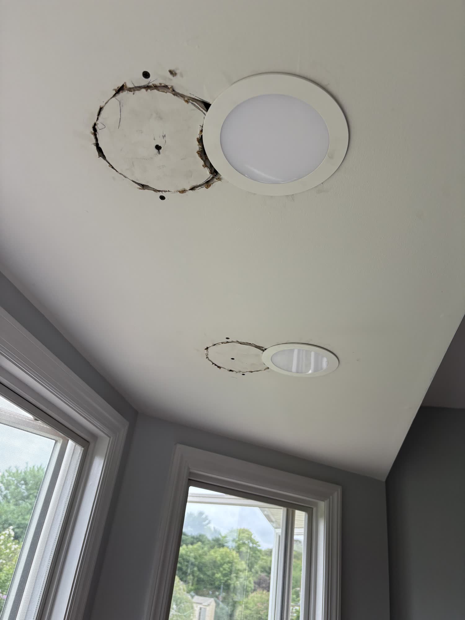 New LED disc lights next to old recessed can holes before patching